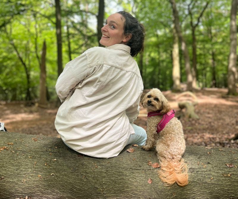 Person and dog sitting on a log.